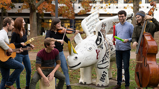 Mehrere MusikerInnen musizieren neben einem geflügelten Nashorn - dem Wappentier des Konzerthauses Dortmund.